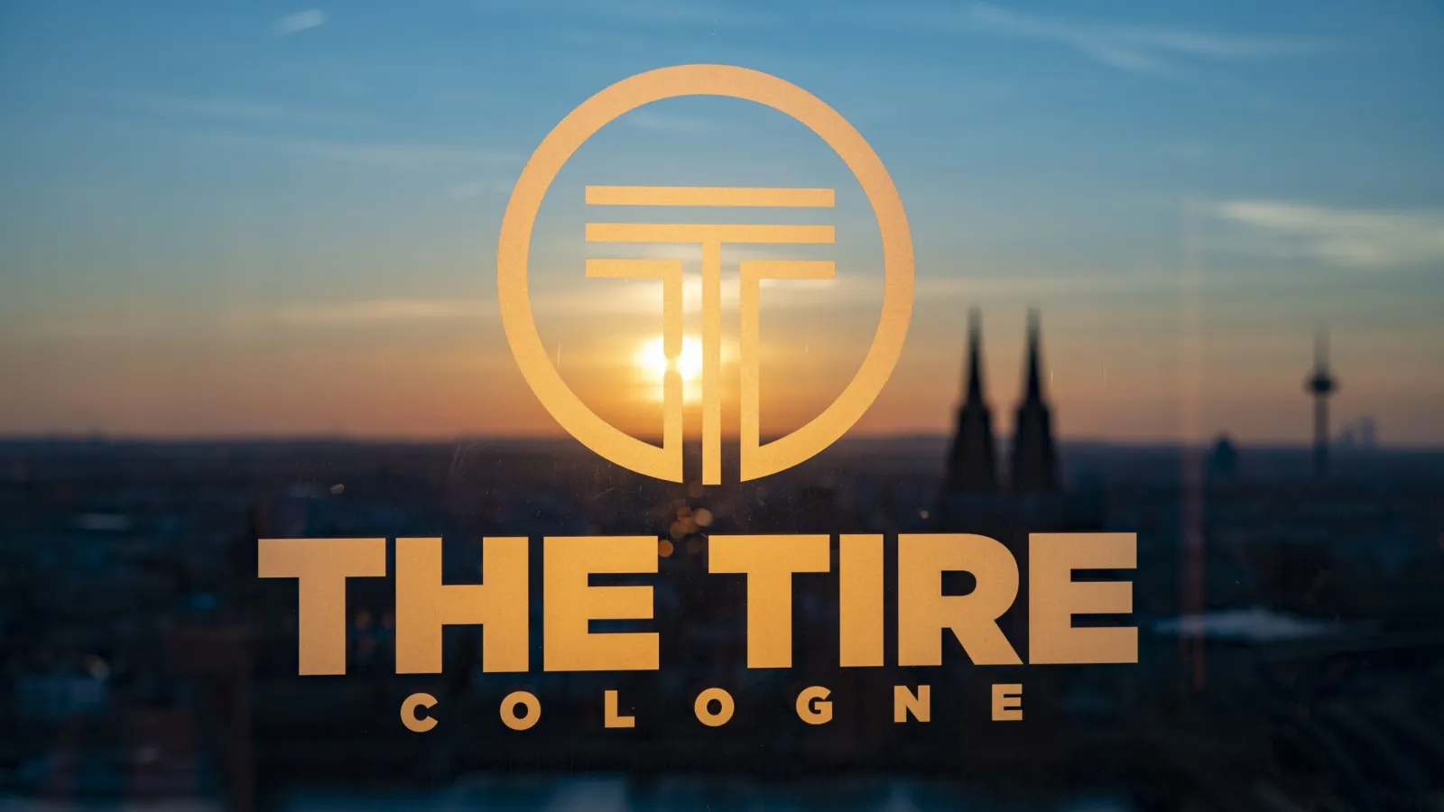 A close-up view of the golden "THE TIRE COLOGNE" logo. (Photo: Koelnmesse / THE TIRE COLOGNE / Pressekonferenz, KölnSky)